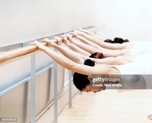 group of dancers in a line stretching at a bar - nick des barres stock-fotos und bilder