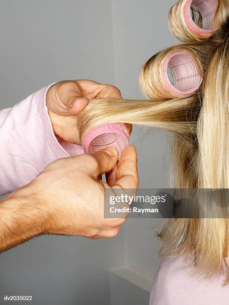 close up of a man's hand putting curlers in a woman's hair - hair curlers stockfoto's en -beelden