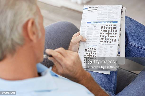 senior man contemplating a newspaper crossword - korsord bildbanksfoton och bilder