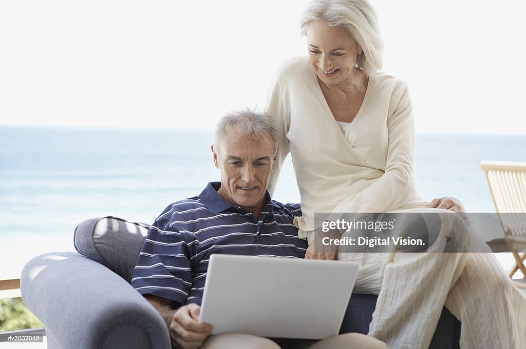 Senior Couple Sitting on an Arm Chair and Looking at a Laptop Computer