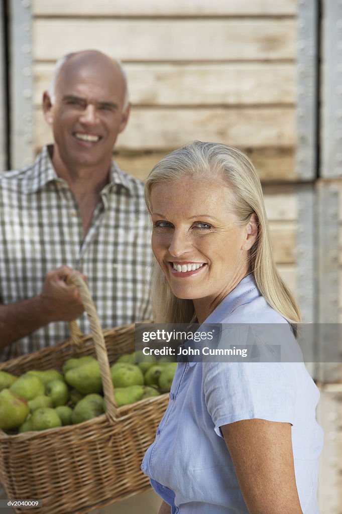 Couple Standing Outdoors, Man Holding a Basket of Pears