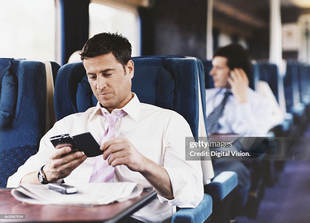 Businessman Looking at His PDA on a Passenger Train