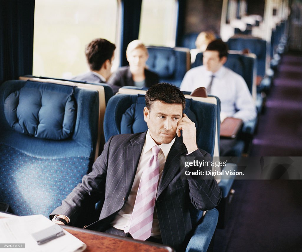 Businessman Sitting on a Passenger Train With His Hand on His Head