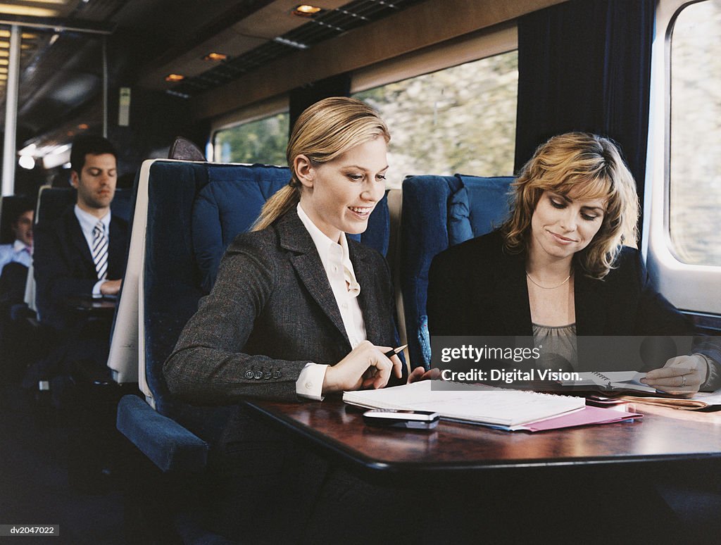 Two Female Business Executives Examining a Document on a Passenger Train