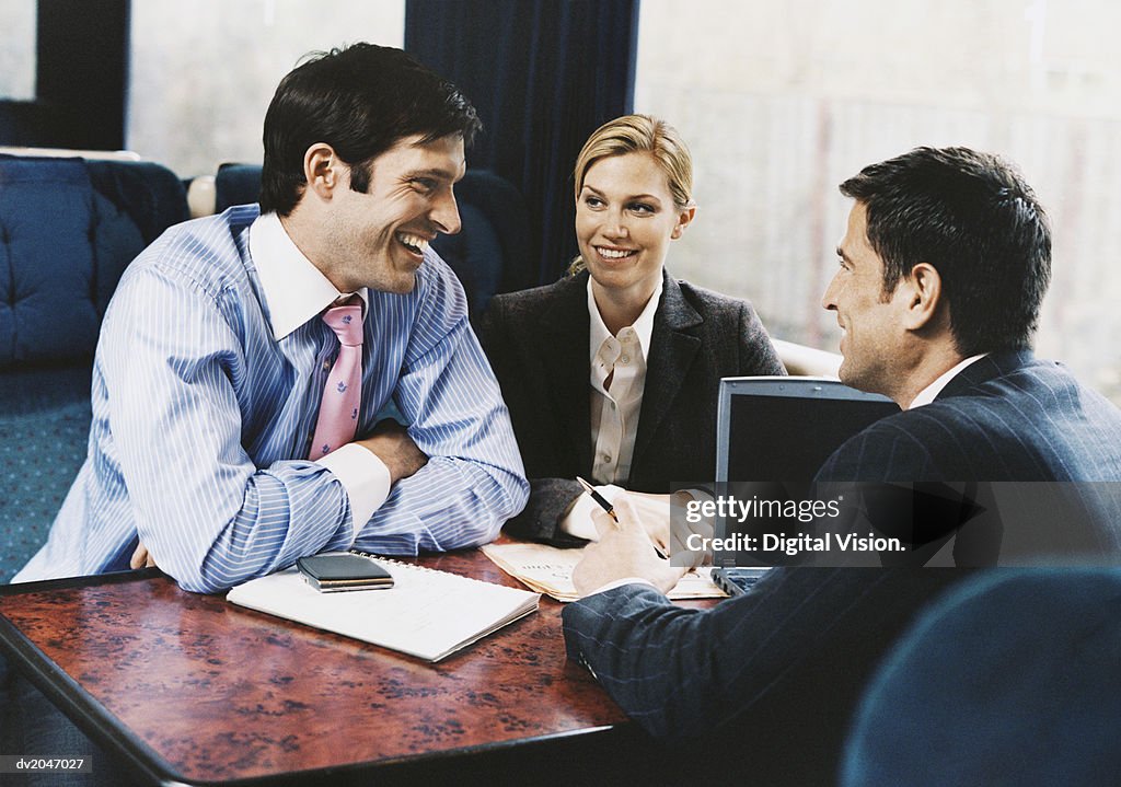 Three Smiling Business Executives Having a Discussion on a Passenger Train