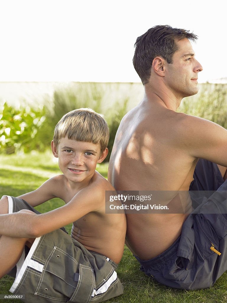 Young Boy Sitting Back to Back with His Father