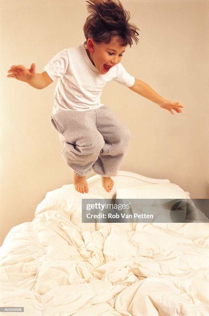 Young boy jumping on bed