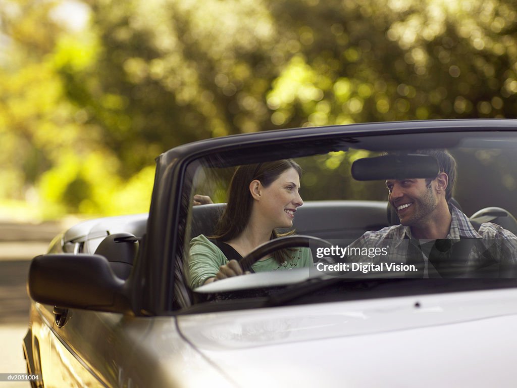 Couple Sit in the Front Seat of a Convertible, Smiling and Gazing at Each Other