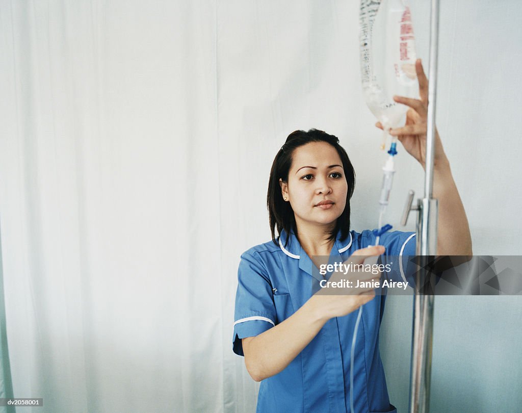 Female Nurse Checks an Intravenous Drip