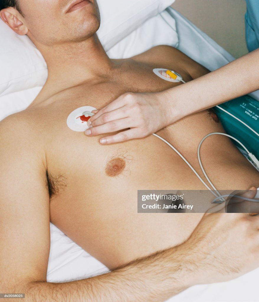 Nurse Adjusts an ECG Pad on a Male Patient's Chest