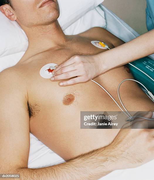 nurse adjusts an ecg pad on a male patient's chest - padding 個照片及圖片檔