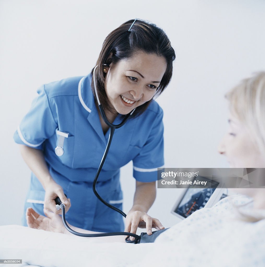 Female Nurse Takes a Patient's Blood Pressure With a Stethoscope