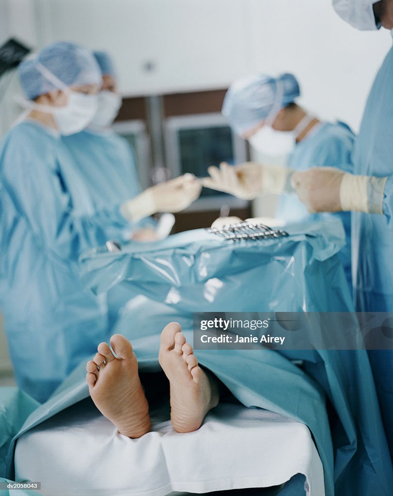 Patient's Feet, Four Surgeons Operating on Him