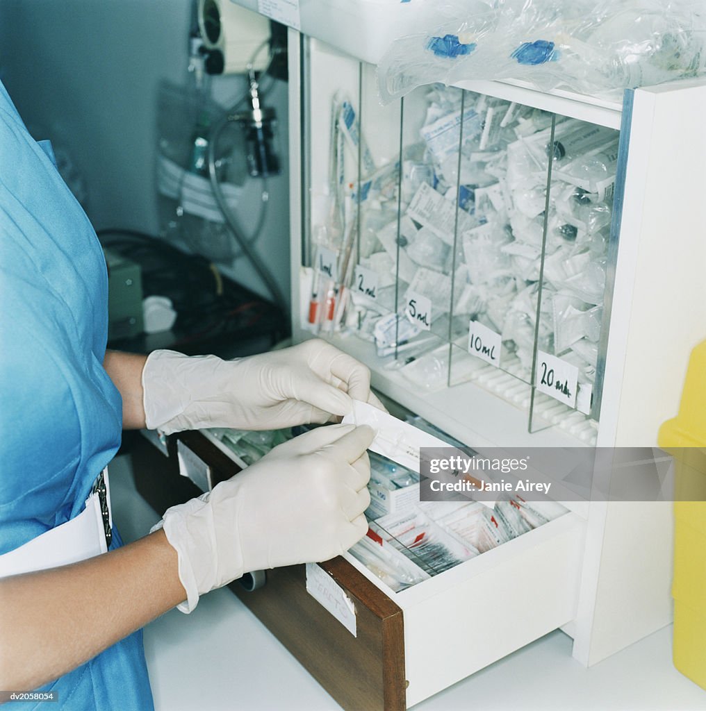 Female Nurse Wearing PVC Gloves Opening a Packed Syringe