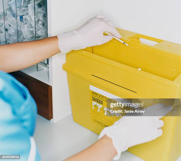 female nurse disposing of a syringe in a waste box - behållare för farligt avfall bildbanksfoton och bilder