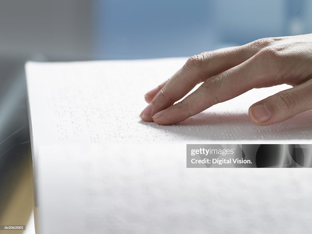 Close Up of a Hand Touching a Braille Book