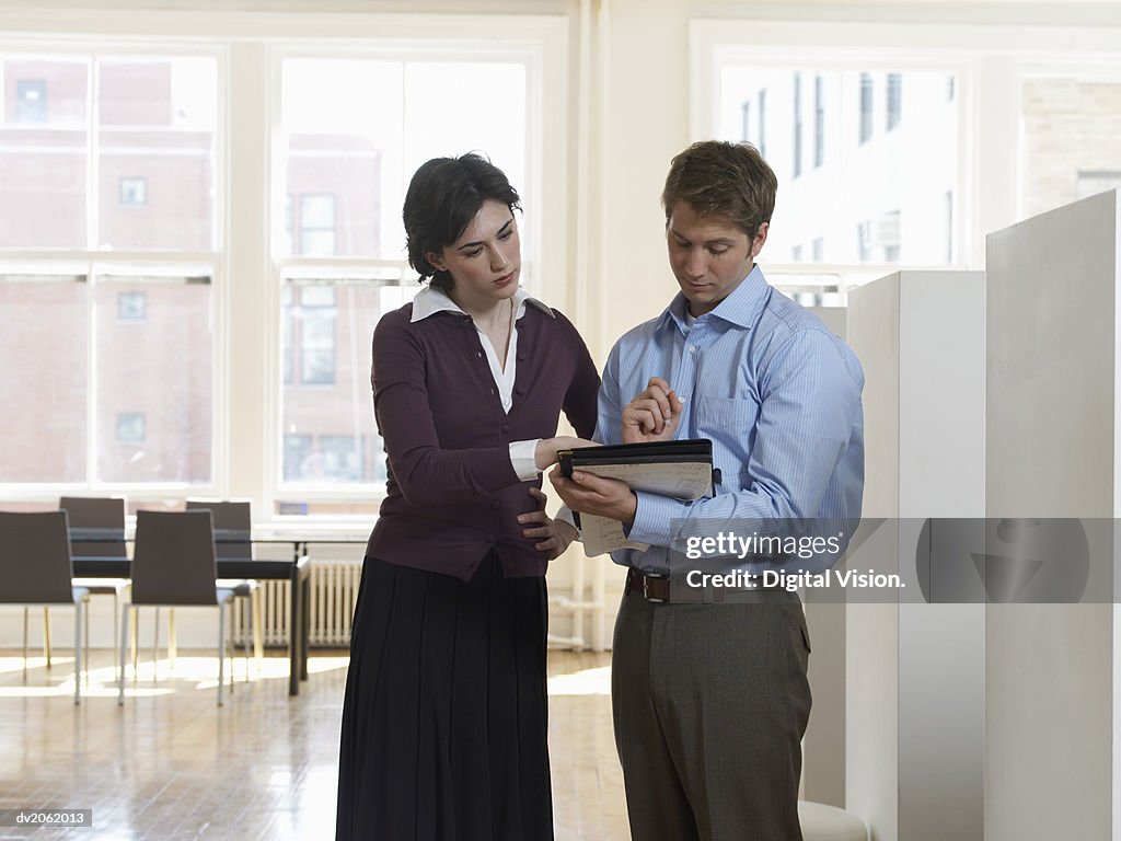Businessman and Businesswoman Examining a Document in a Folder