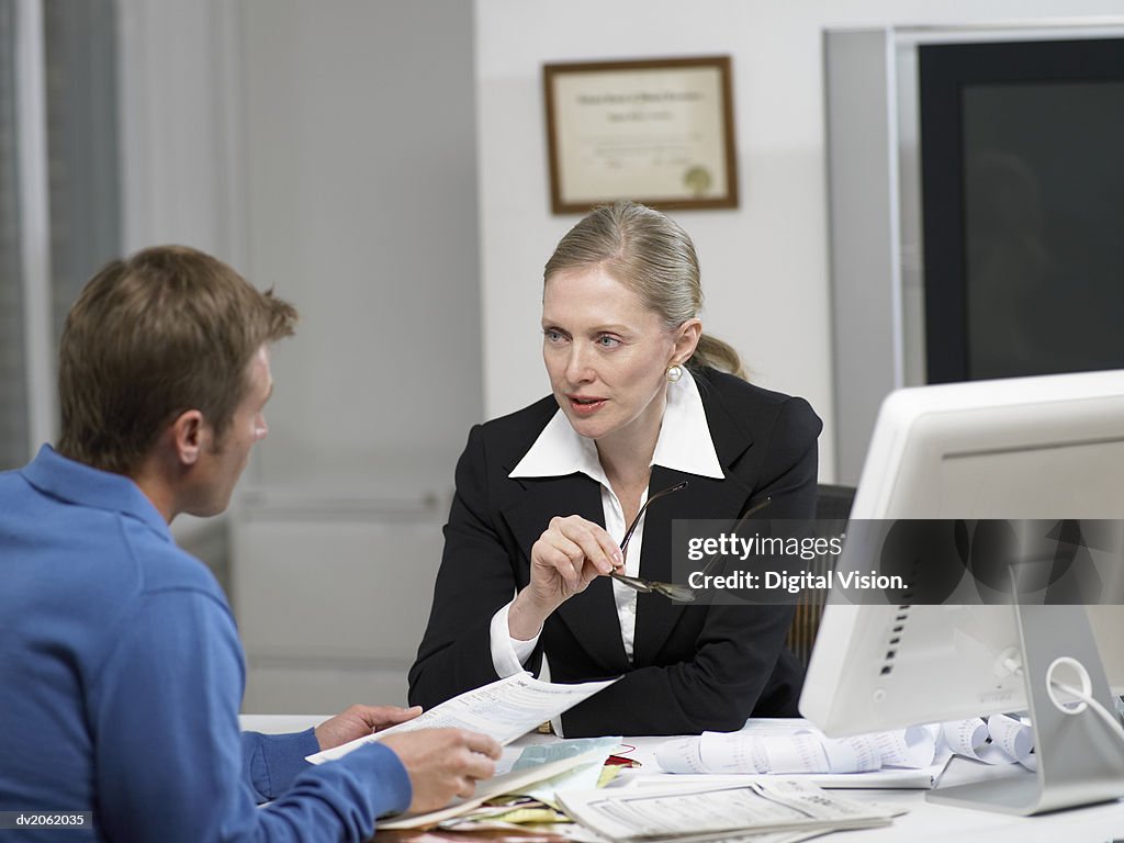 Female Doctor Sitting at Her Desk and Talking to a Male Patient