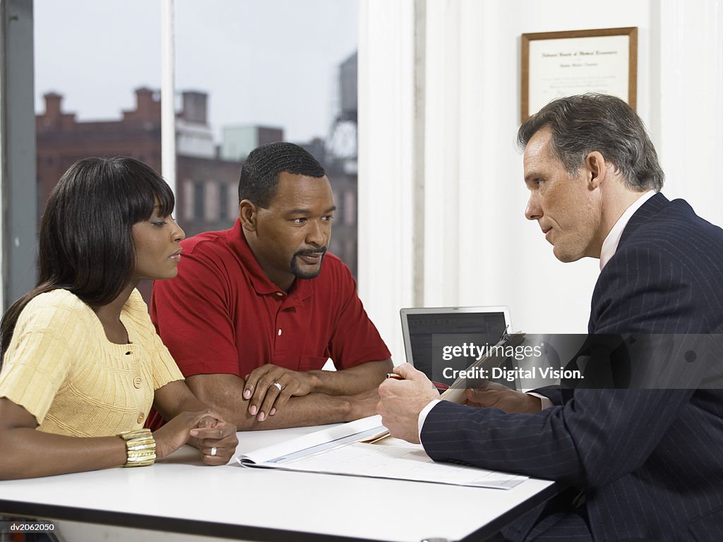 Doctor Explaining a Document to a Couple at His Clinic