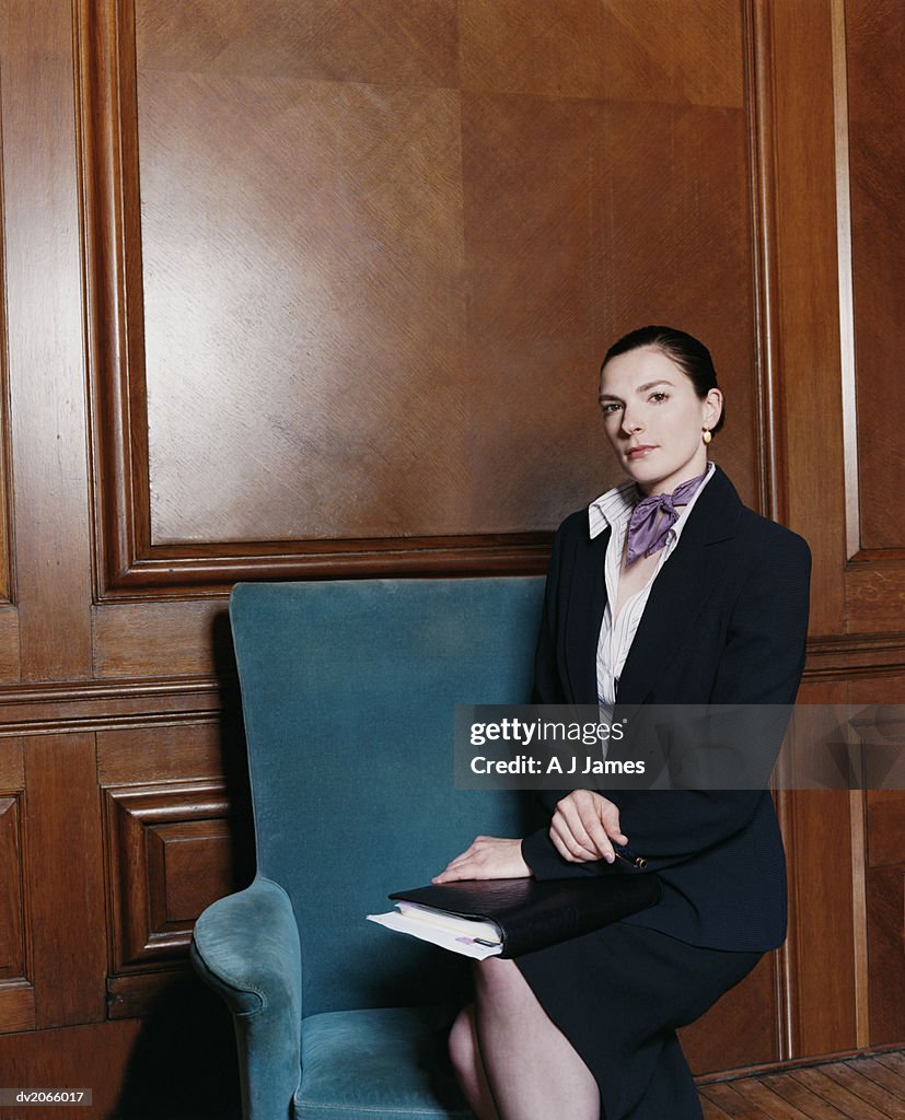 Portrait of a Businesswoman Sitting on an Armchair With a Folder on Her Lap