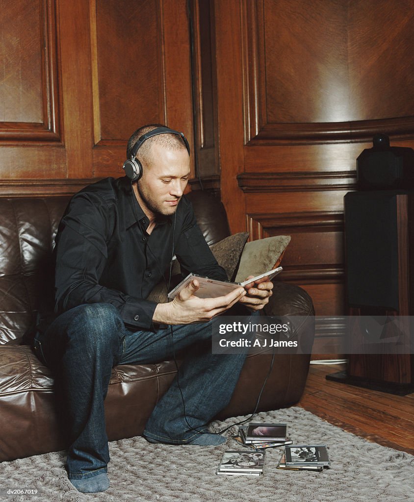 Man Wearing Headphones Looking at Compact Disk Cases