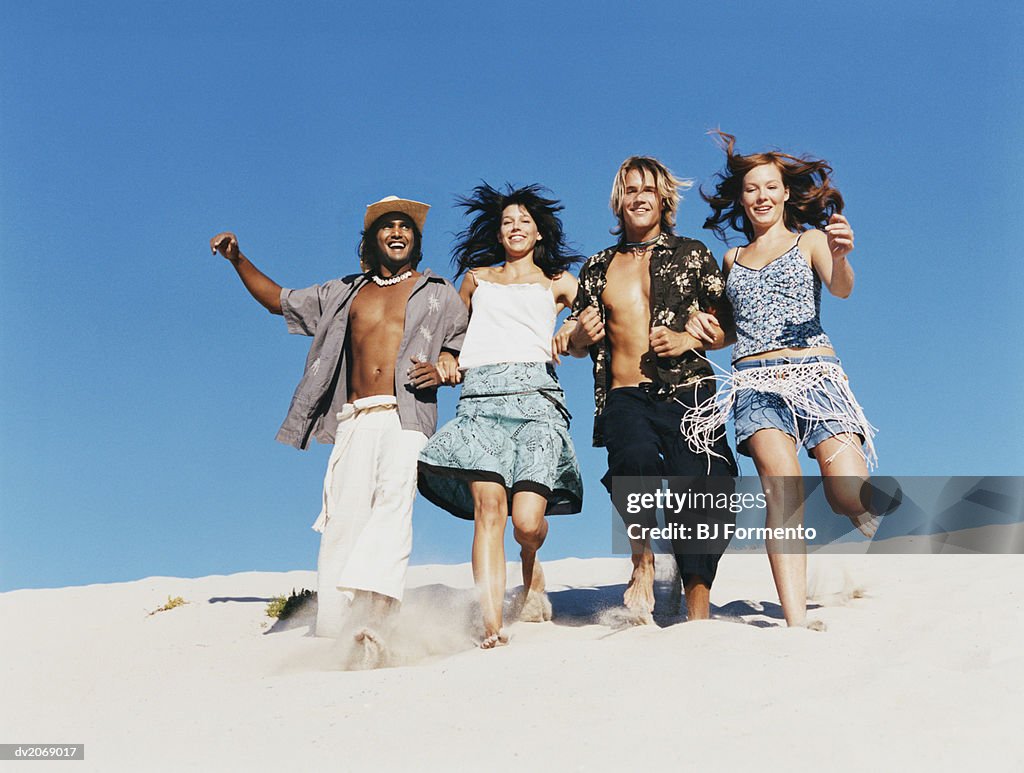 Four people in Summer Outfits Walking Arm in Arm on a Dune