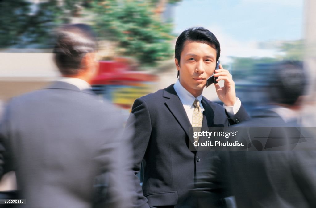 Businessman talking on phone, people rushing by