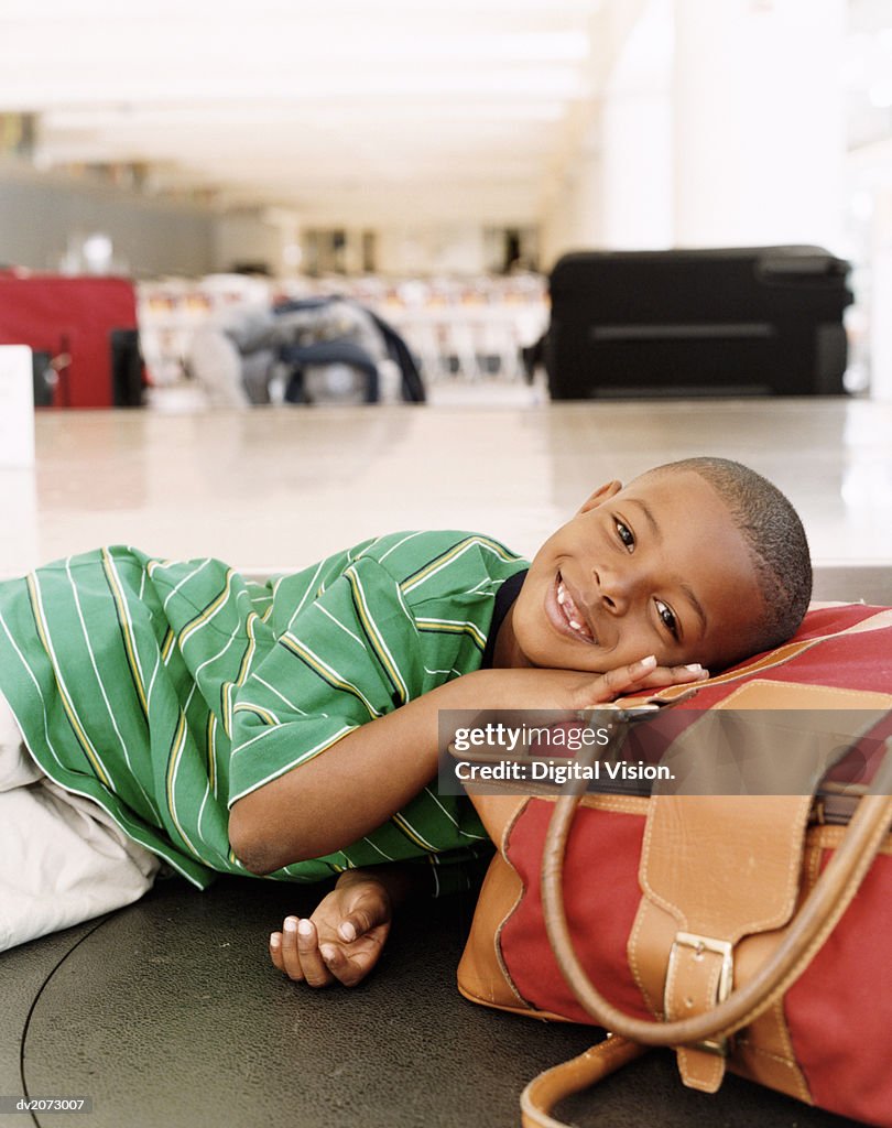 Boy Lying on Luggage on an Airport Baggage Conveyor Belt
