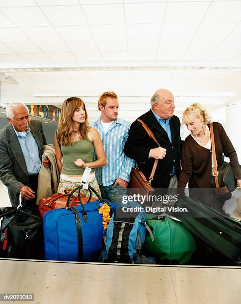 passengers at an airport baggage collection searching for their luggage - searching for something ストックフォトと画像