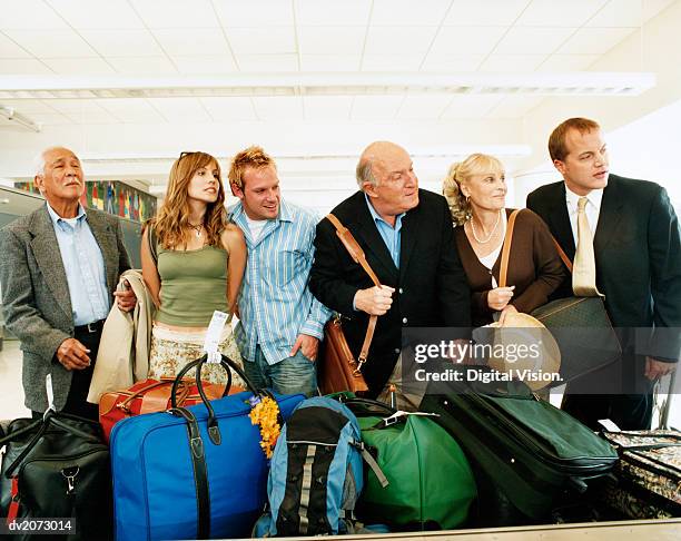 passengers at an airport baggage collection searching for their luggage - searching for something ストックフォトと画像