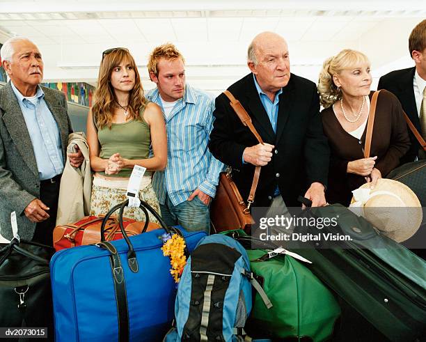 passengers at an airport baggage collection searching for their luggage - searching for something ストックフォトと画像