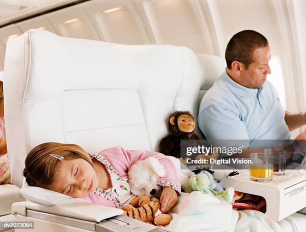 girl asleep and her father sitting beside her in an aircraft cabin - digital devices beside each other bildbanksfoton och bilder