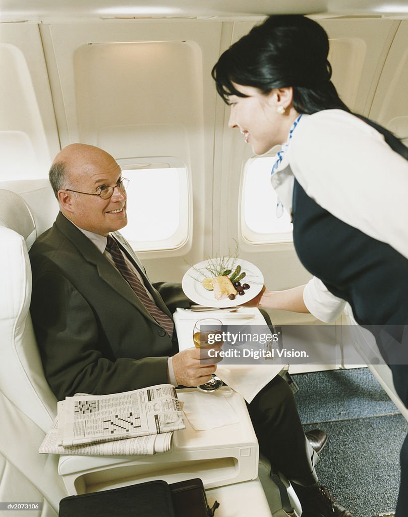Stewardess Serving a Meal to a Businessman in an Aircraft