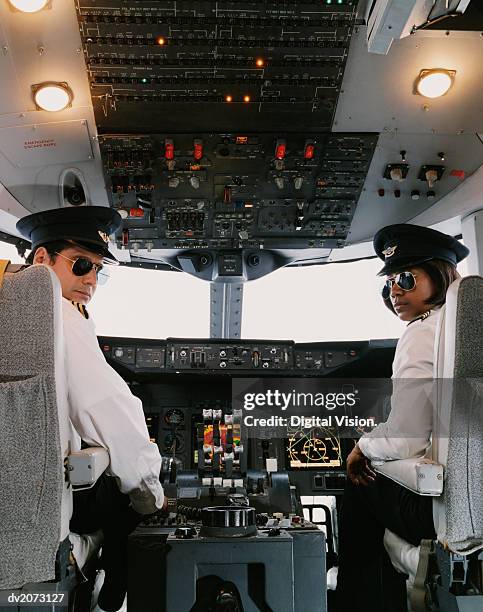 portrait of male and female pilots sitting in the cockpit - berretto da uniforme foto e immagini stock