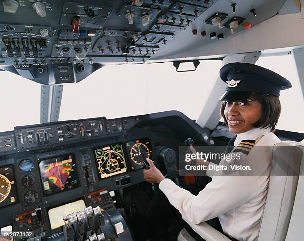 portrait of a female pilot sitting in the cockpit - berretto da uniforme foto e immagini stock