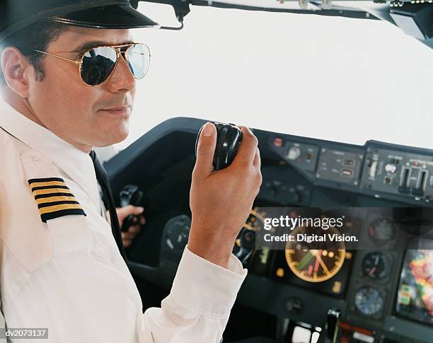 portrait of a male pilot sitting in the cockpit holding a radio - walkie talkie stock pictures, royalty-free photos & images