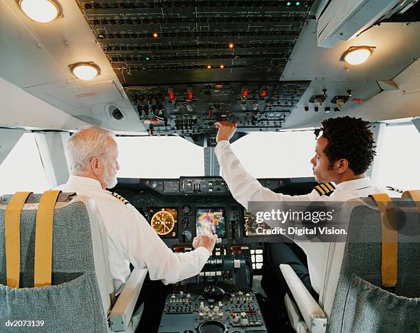 portrait of pilots sitting in the cockpit, adjusting the controls - aviatrice stock-fotos und bilder