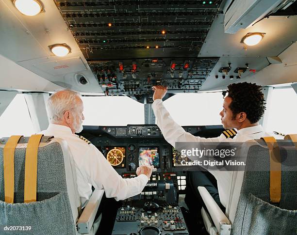 portrait of pilots sitting in the cockpit, adjusting the controls - piloto fotografías e imágenes de stock