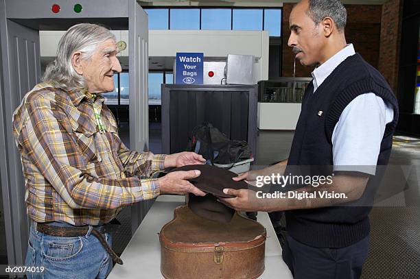 old male cowboy at an airport security check showing a customs official his empty hat - male airport stock pictures, royalty-free photos & images