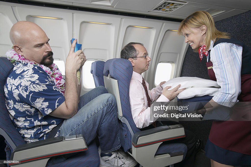 Air Stewardess Giving a Businessman a Pillow During a Flight