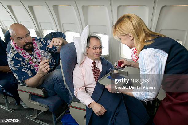 air stewardess pouring a drink for a businessman on a plane - airplane tray stock-fotos und bilder