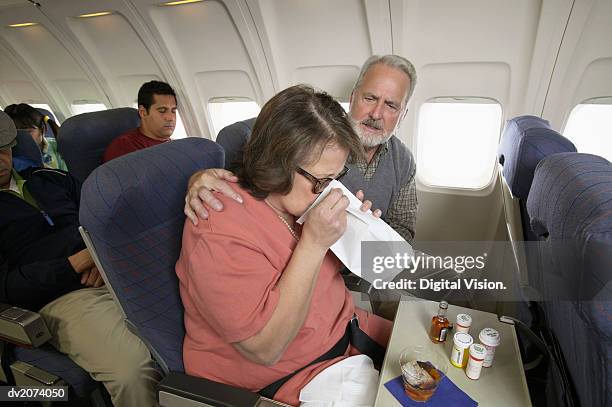 senior woman vomiting into a sick bag during a flight on a plane - sick bag fotografías e imágenes de stock
