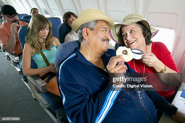 senior couple sitting in an aircraft cabin eating and drinking - super sensory stock pictures, royalty-free photos & images