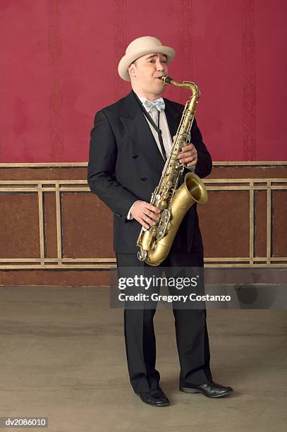 male saxophonist performs on stage in a suit and porkpie hat - porkpie hat stock-fotos und bilder