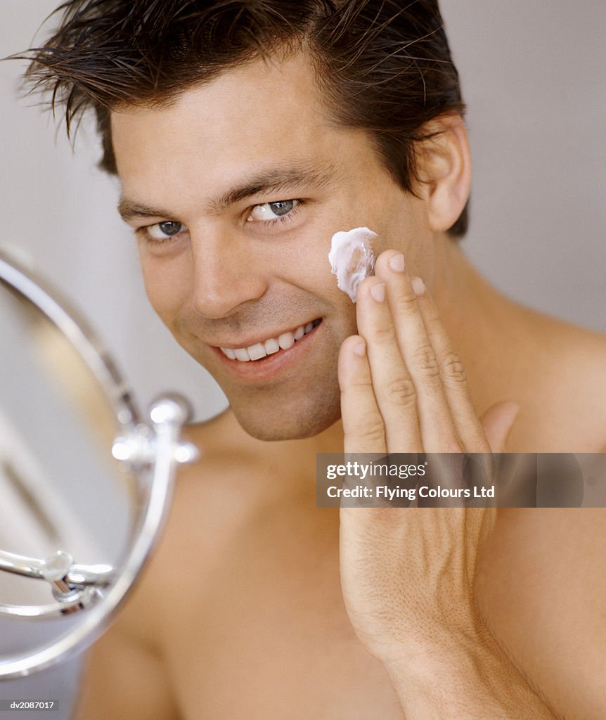 Smiling Man Applying Moisturizer to His Face