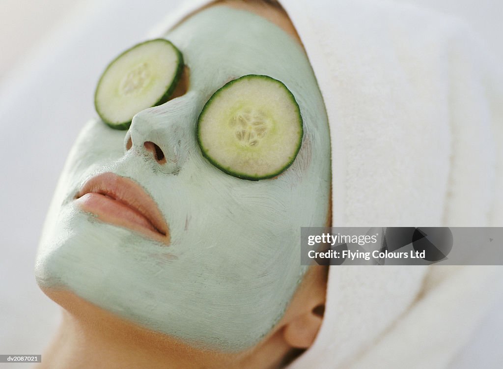 Young Woman Lying Down With a Face Pack and a Towel Wrapped Around Her Head