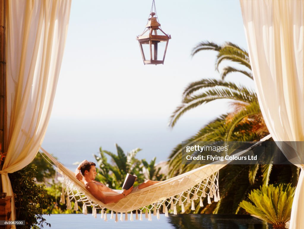 Man Lying in Hammock Reading a Book