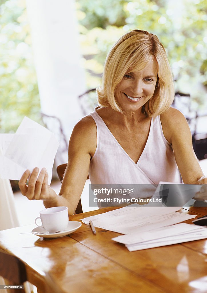 Mature Woman Sitting at a Table Organising Her Bills