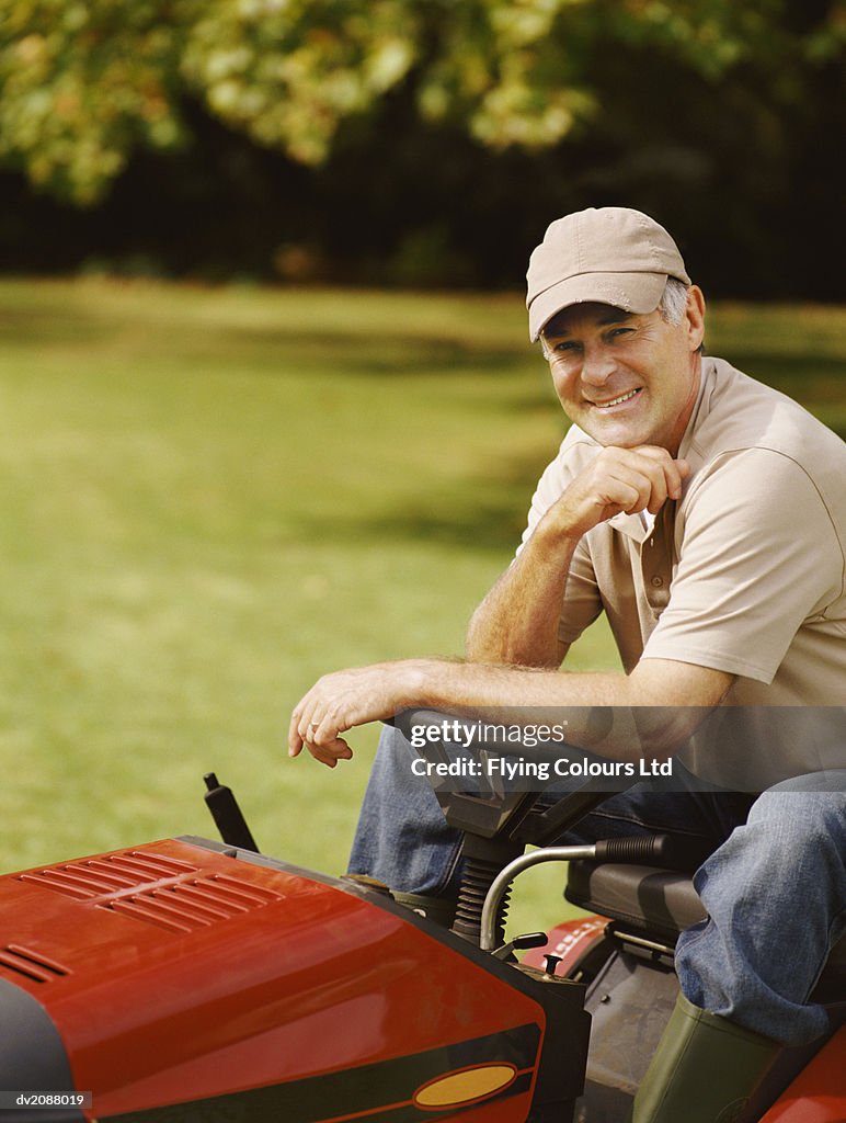 Mature Man Sitting in a Garden on a Lawnmower