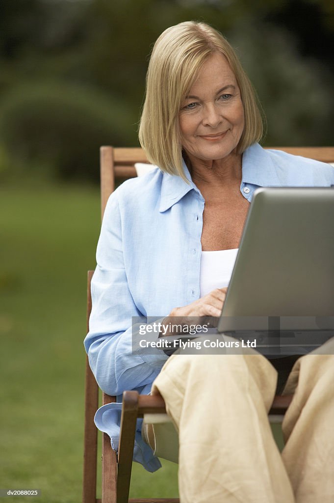 Senior Woman Sitting With a Laptop in Her Garden